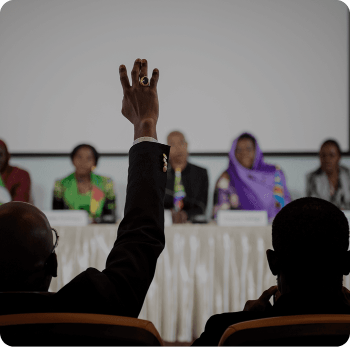 Attendee raising a hand to ask a question at a panel session